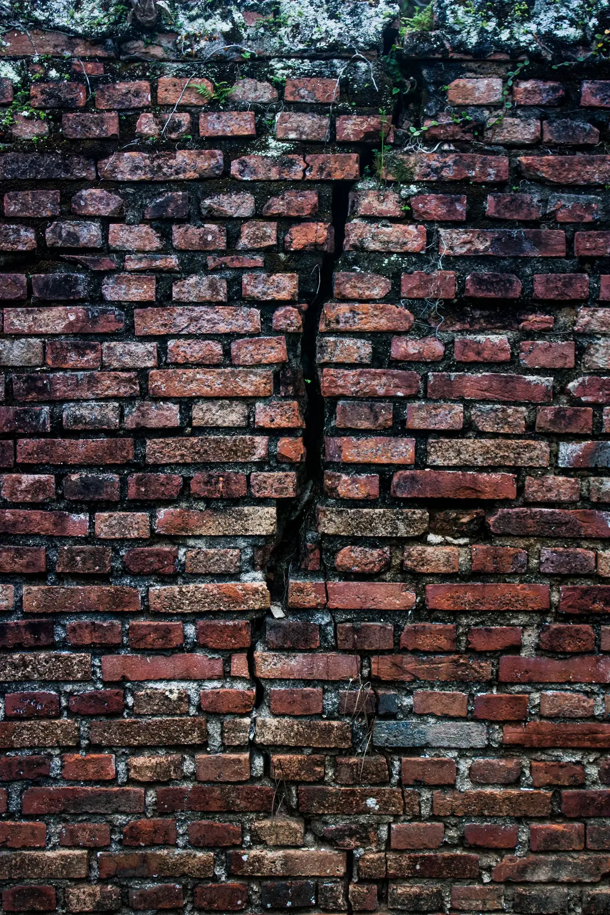 Close-up of an old brick wall with a long crack through the mortar.